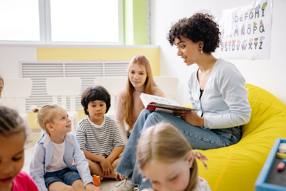 Teacher reading to young children in a colourful classroom with alphabet poster